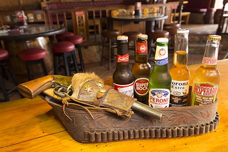 A Variety of Bottle Beers next to a Gun